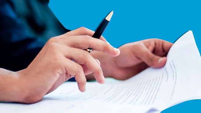 hand with pen poised over contract